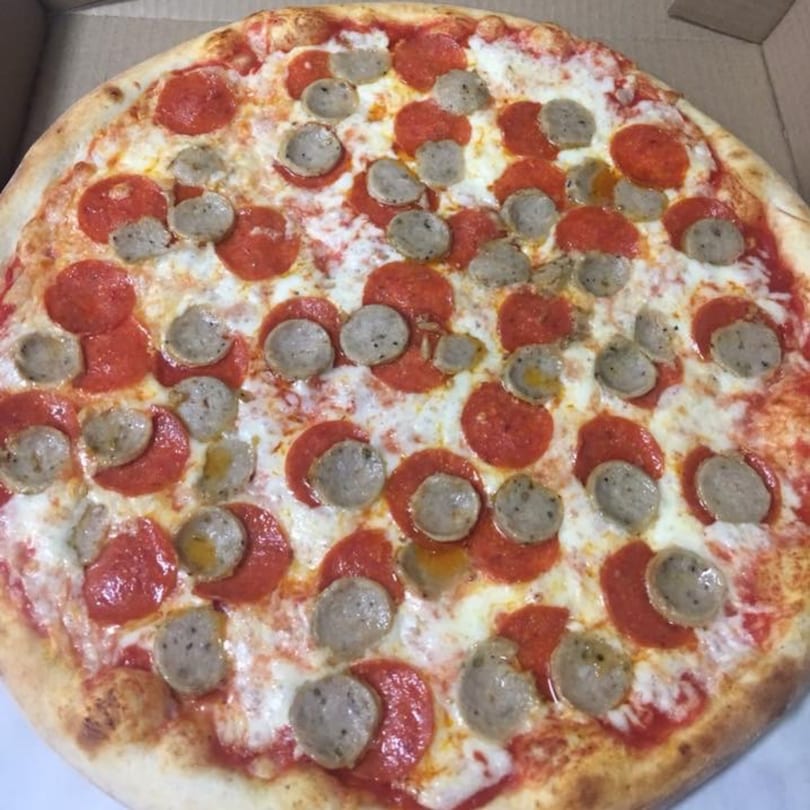 A whole pepperoni and sausage pizza from Pizza Village V, in a cardboard box.