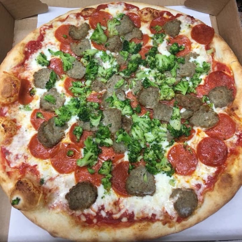 A Pizza Village V pizza with pepperoni, sausage, and broccoli in a cardboard box.