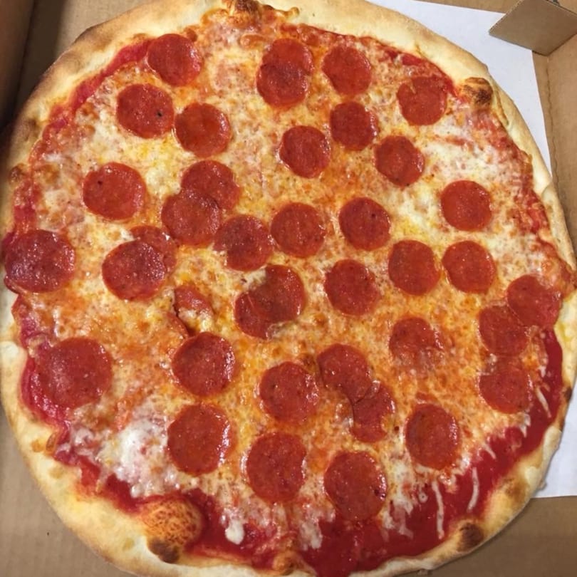 A whole pepperoni pizza from Pizza Village V, with melted cheese and a crispy crust, in a box.