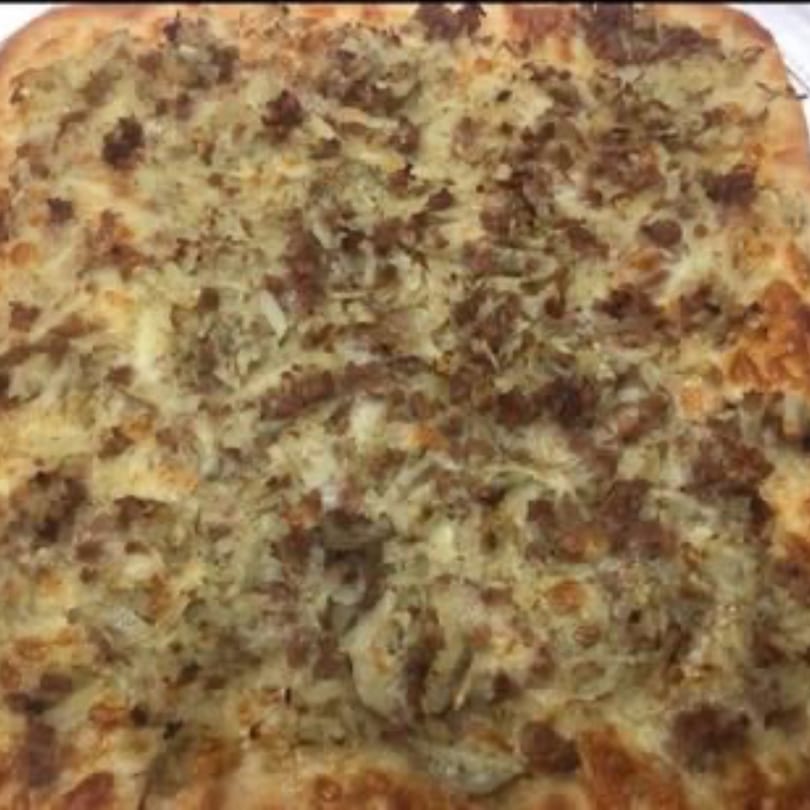 Close-up of a square pizza from Pizza Village V, topped with sausage and onions.