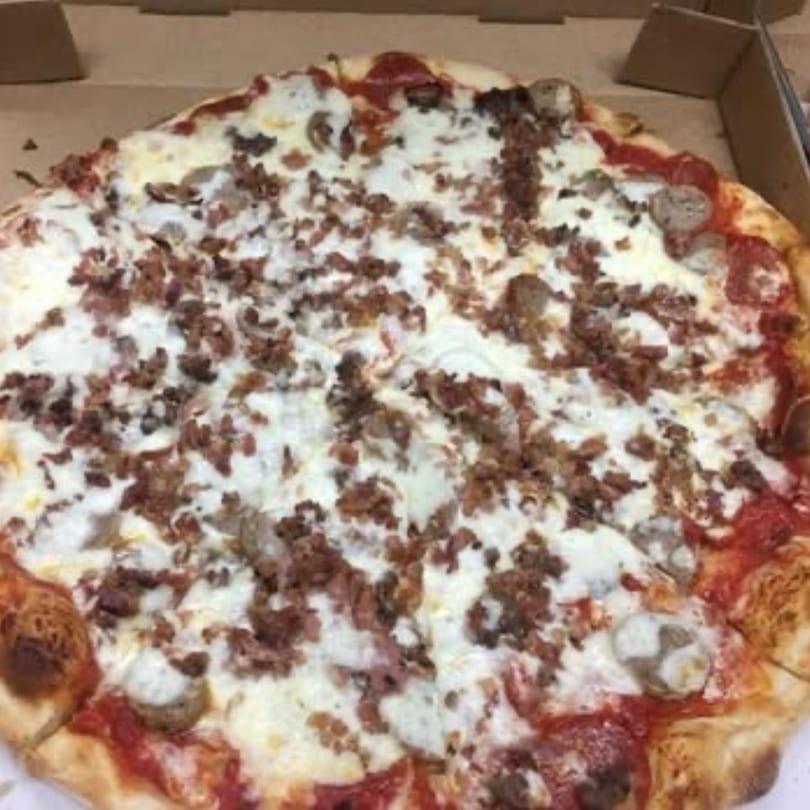 A whole Pizza Village V pizza with white cheese, pepperoni, sausage, and ground meat toppings.